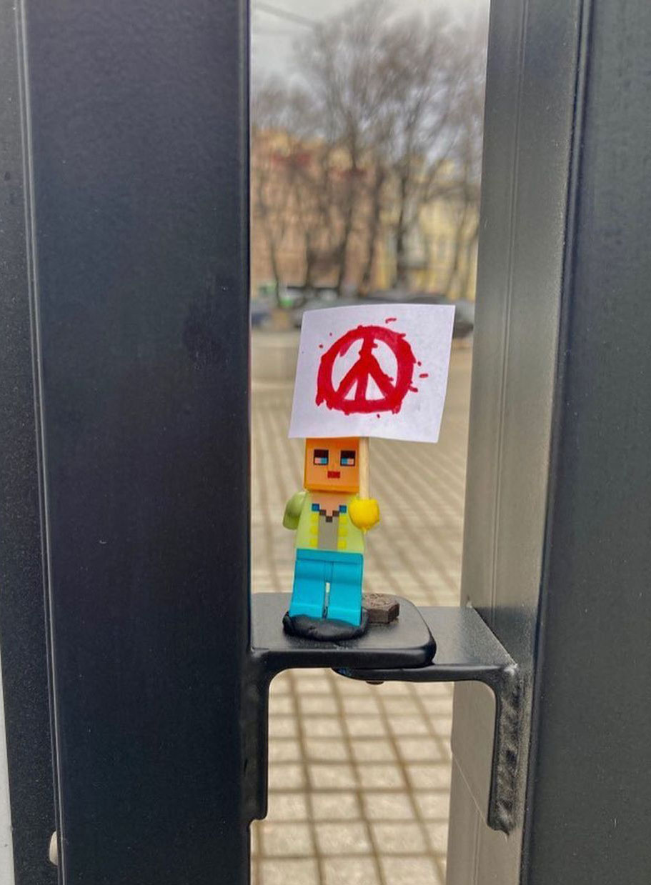 A Lego figurine holding a peace poster.