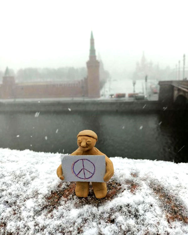 A yellow figurine holding a peace card.