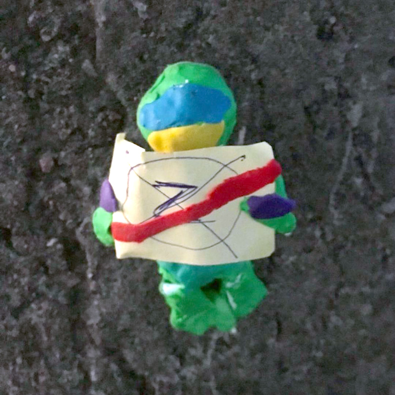 A clay figurine with a poster of a letter Z crossed out.